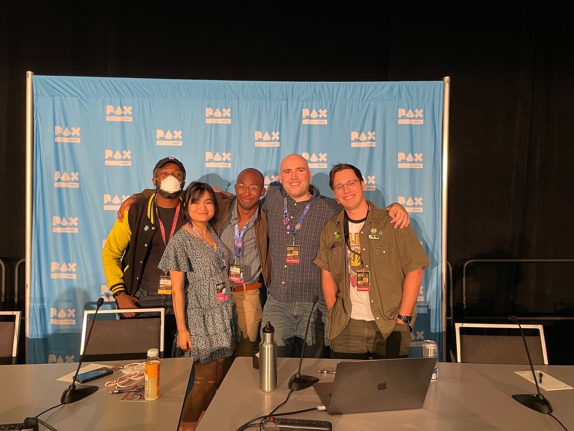 5 people standing in front of a PAX photo backdrop.